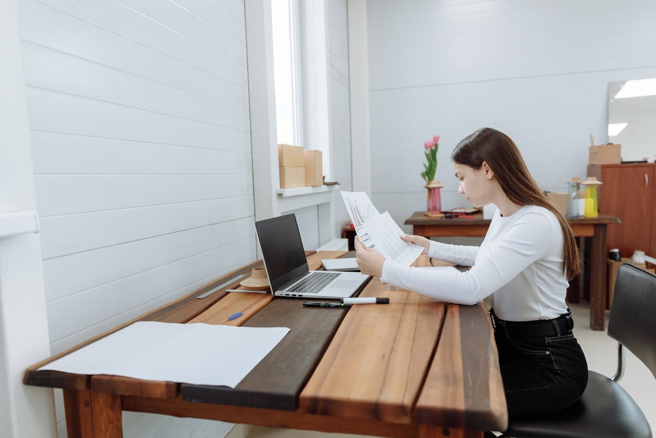 woman on laptop desk looking at papers